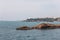 Unique rocky coastal formations repeating shape of sea waves, with lighthouse in background.Â Biarritz